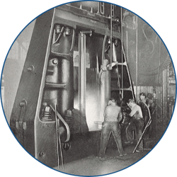 A black and white image of men operating a large forging hammer.