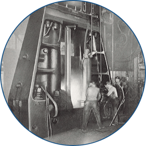 Black and white photo of men working around a forging hammer.